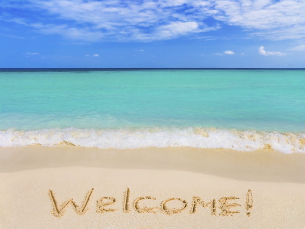 the word welcome written in sand by the seaside