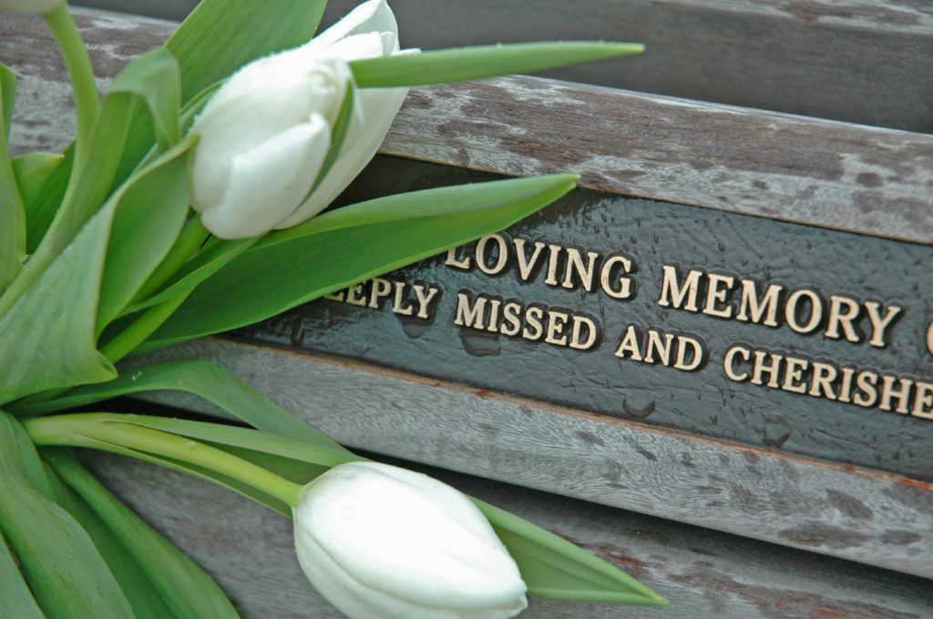 Tombstone heading reading in loving memory covered in flowers