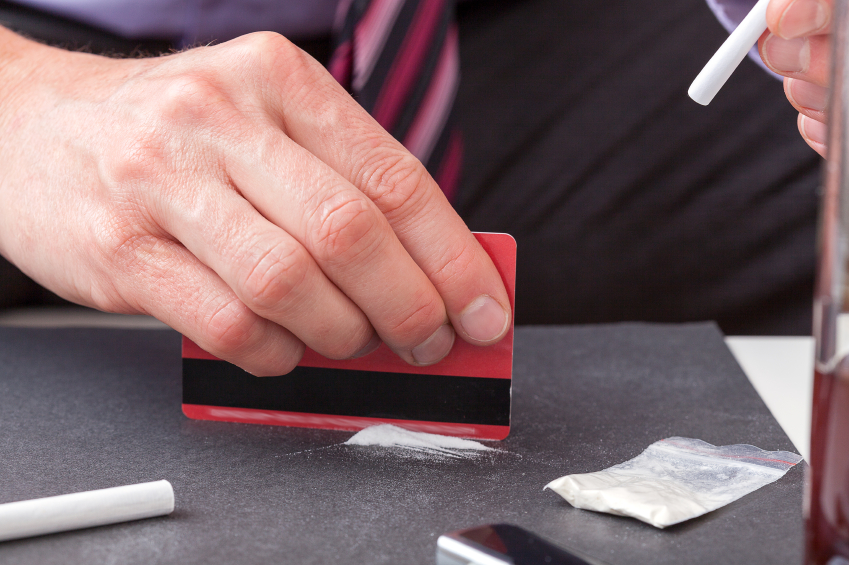 Businessman cutting cocaine to snort.