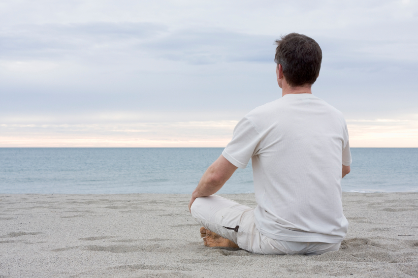 Man  at peace sitting on beach meditating.