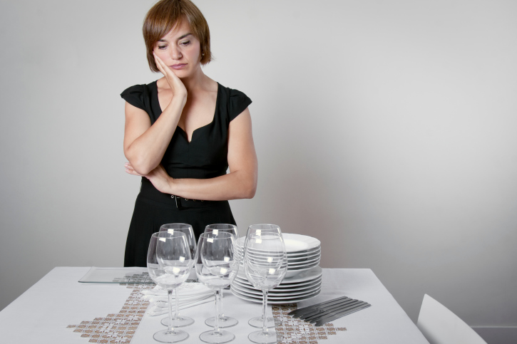 Bored depressed housewife setting the table for company.