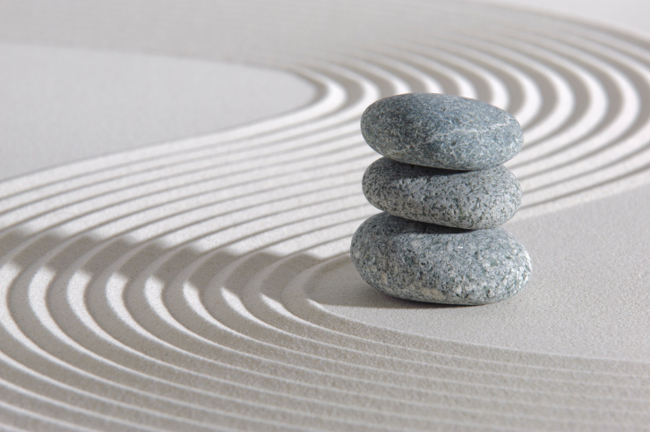 Concept of Buddism showing piled stones on sand.