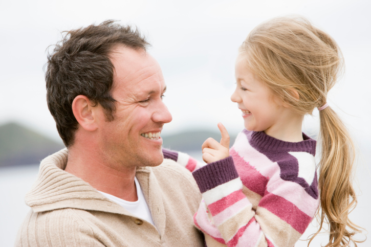 Father hugging his young daughter at beach.