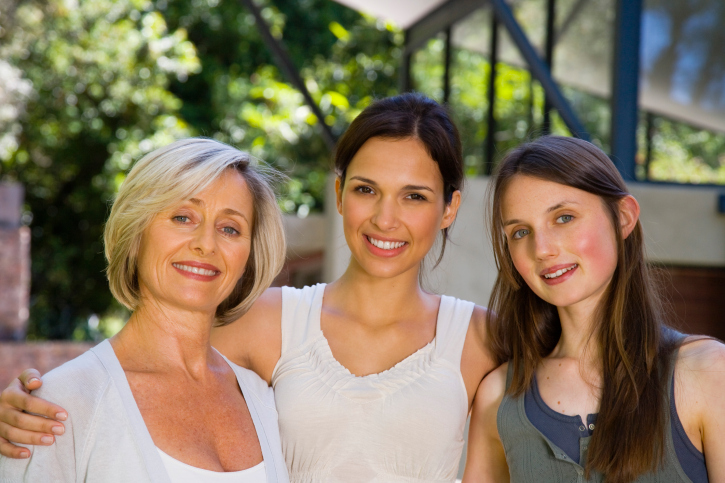 Mother and young adult daughters hugging.