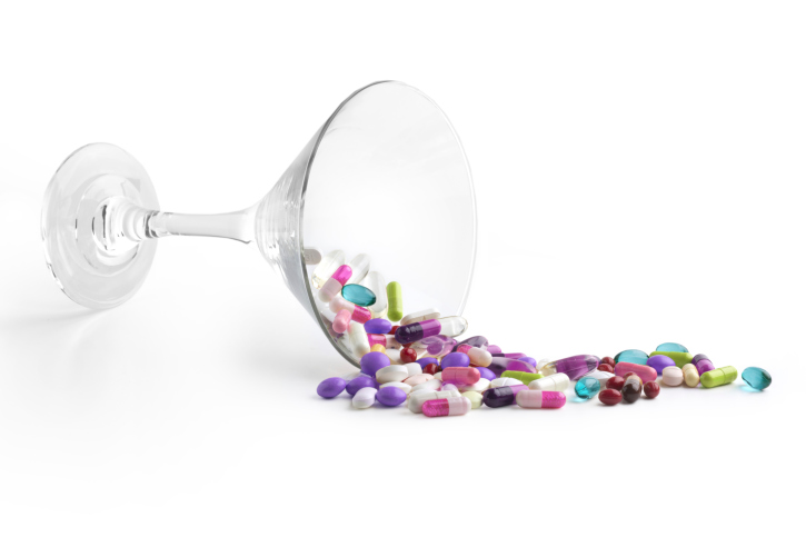 Painkillers pouring out of a martini glass.