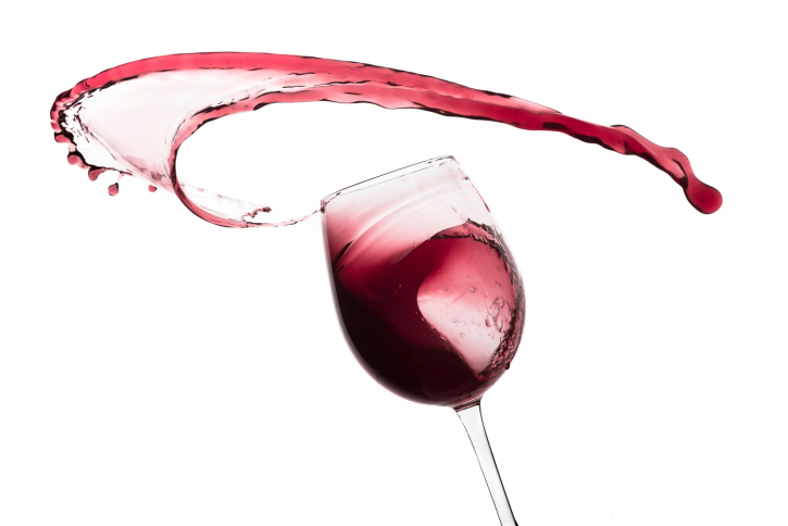 Red wine splashing out of glass.