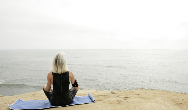 Woman sitting doing yoga on the beach.