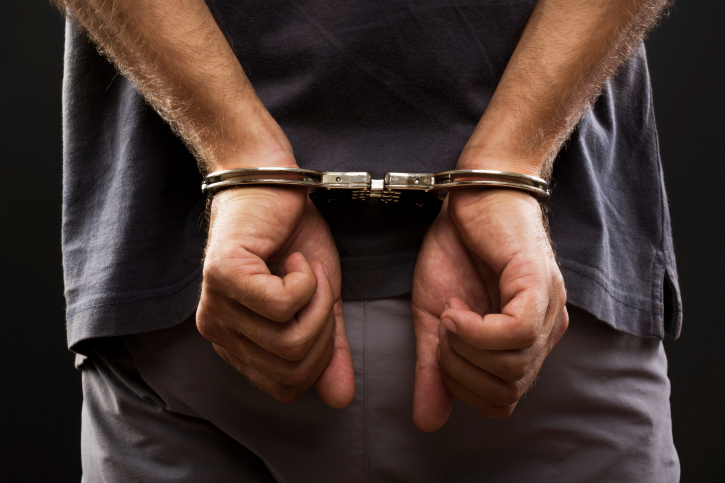 photo of a young man in handcuffs after being arrested