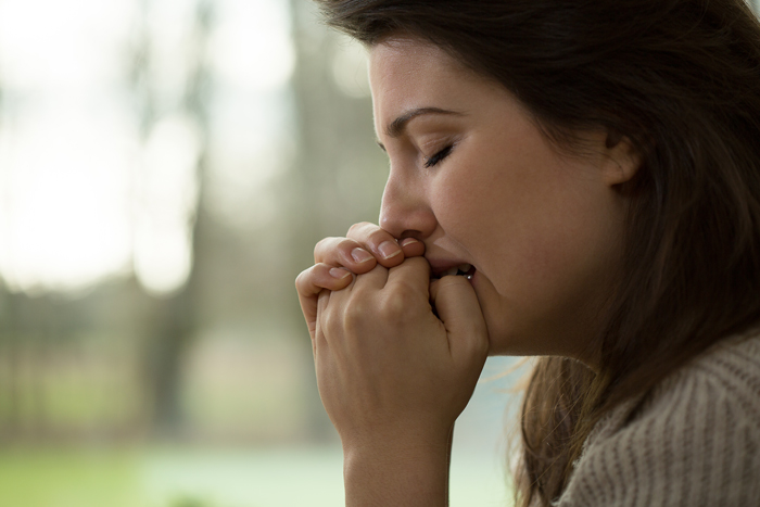 photo of a sad woman crying and holding her hands to her mouth